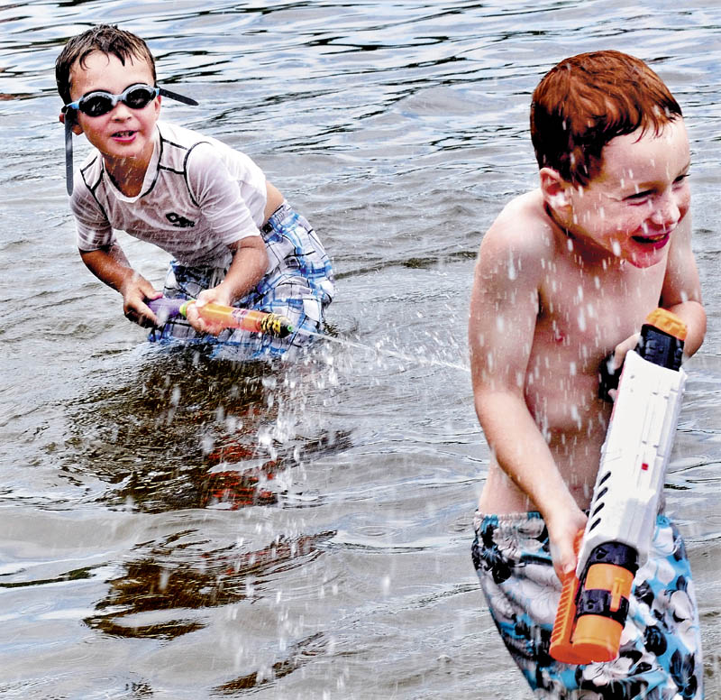 Noah McMahon, left, blasts Camden Herrick with a water gun while cooling off at Lake George Regional Park in Canaan on a hot and humid Friday.