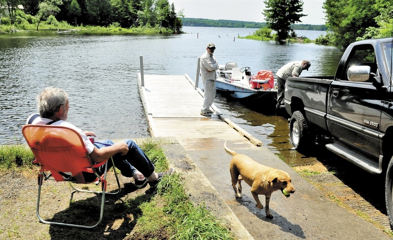 Kip Keating, left, watches his dog Tera retrieve a ball from Lake Wesserunsett in East Madison on Friday as Ray Harding, center, and Ken Binnion pull their boat out after fishing. The ice on the lake went out on March 23 this spring, sooner than any year previously recorded.