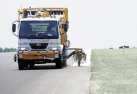 A truck paints the edge of the newly repaved runway that reopened on Friday at the Augusta State Airport. The project included narrowing the width of the runway.