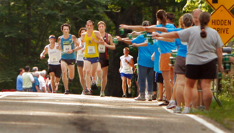 Volunteers hold out water to runners along Shore Road in Cape Elizabeth during last year's TD Bank Beach to Beacon 10K.
