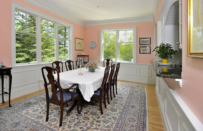 The formal dining room is surrounded by evergreens outside.