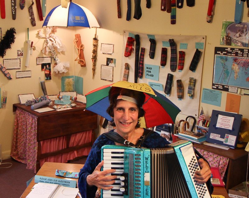 Director and curator Nancy 3. Hoffman accompanies herself on the accordion while singing the museum theme song, “Let a Smile Be Your Umbrella.”
