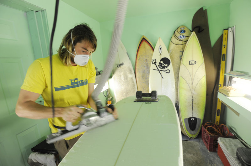 Andy McDermott, 28, shapes a board at Black Point Surf Shop.