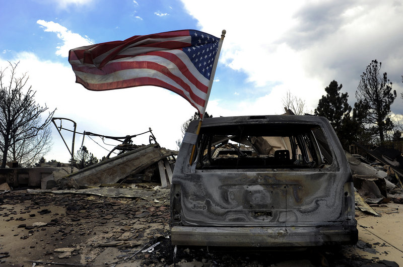 A flag flies on a burned car in Colorado Springs, Colo., where residents were allowed to visit their homes Sunday after the Waldo Canyon fire ravaged their neighborhood.