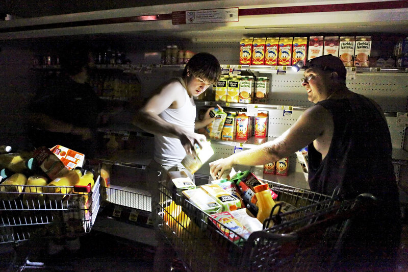 David Robertson and Steve Jones fill their shopping cart with juice Monday at the darkened Mick-or-Mack IGA grocery store in New Castle, Va. Supermarkets around the region struggled to keep groceries from going bad.