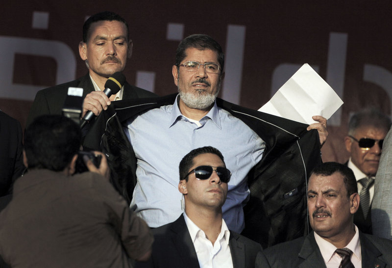 Egyptian President-elect Mohammed Morsi opens his jacket Friday to show his supporters that he is not wearing a bullet-proof vest.