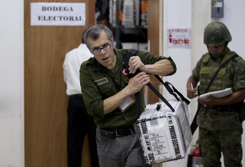 An electoral official carries a ballot box Wednesday in Mexico City. With 99 percent of the vote tallied in the preliminary count, Enrique Pena Nieto of the PRI, led with 38 percent of the vote in the presidential election.