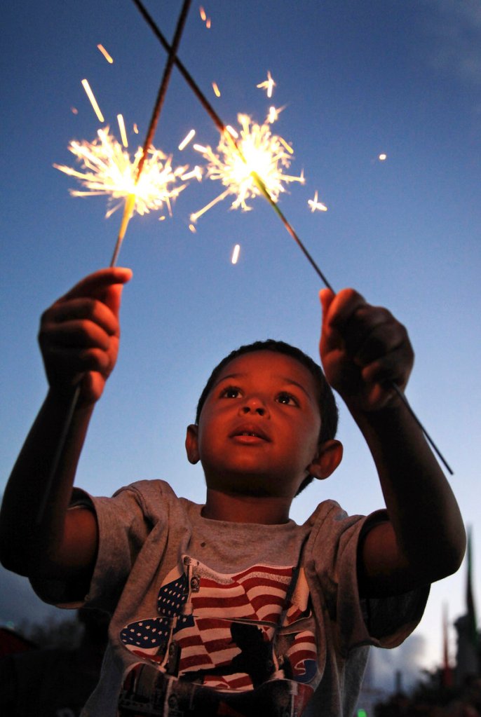 Quin Lucas, 4, in Portland on vacation from Pennsylvania, lights up the night with sparklers while waiting for the fireworks with his parents, Heather and Quasar, at the Eastern Prom in Portland on Thursday.