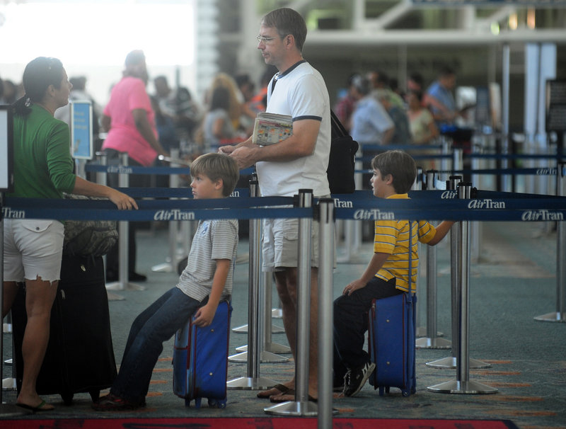 Twin brothers Liam, left, and Rowan Miller, 7, wait in line with their parents, Scott and Cynthia Miller, to board a flight in Ft. Lauderdale, Fla., last week. Families and friends who want to sit next to each other when they fly may have to pay extra as airlines try to sell roomier premium seats. Some airlines also no longer allow families with young children to pre-board.