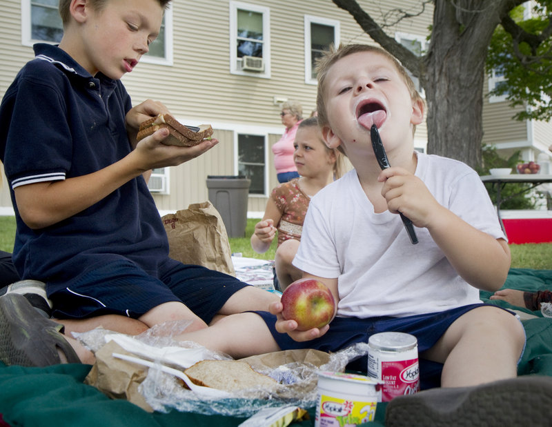 Mason Stoddard, 11, and Nickolas Keene, 3, picnic outside Little Falls Landing senior housing in Windham on Friday. This is the first summer that free lunches have been provided every weekday at the Windham site for children age 18 and under.