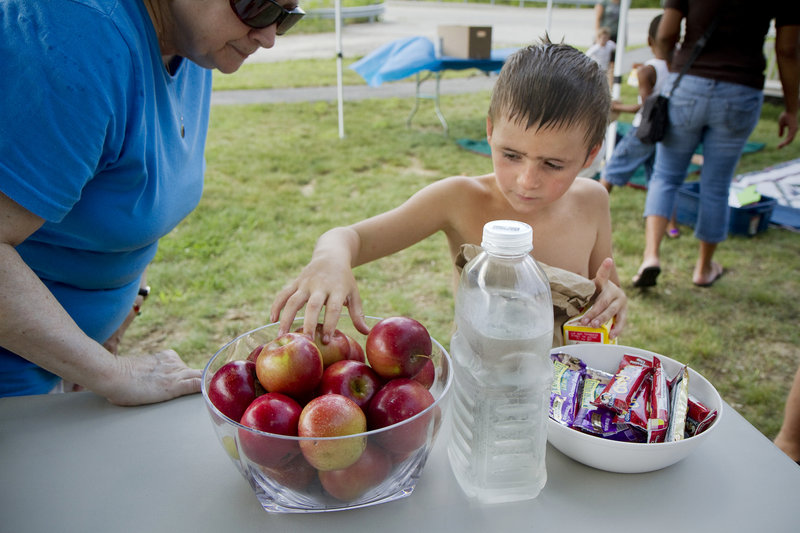 Matthew Keene, 6, of Windham chooses an apple at the free lunch at Little Falls Landing on Friday.