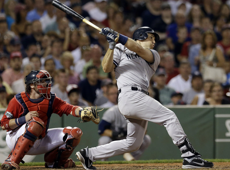 Mark Teixeira of the New York Yankees follows through on a two-run triple in the seventh inning Friday night as Red Sox catcher Jarrod Saltalamacchia watches. The triple was the key hit in the Yankees’ 10-8 victory.