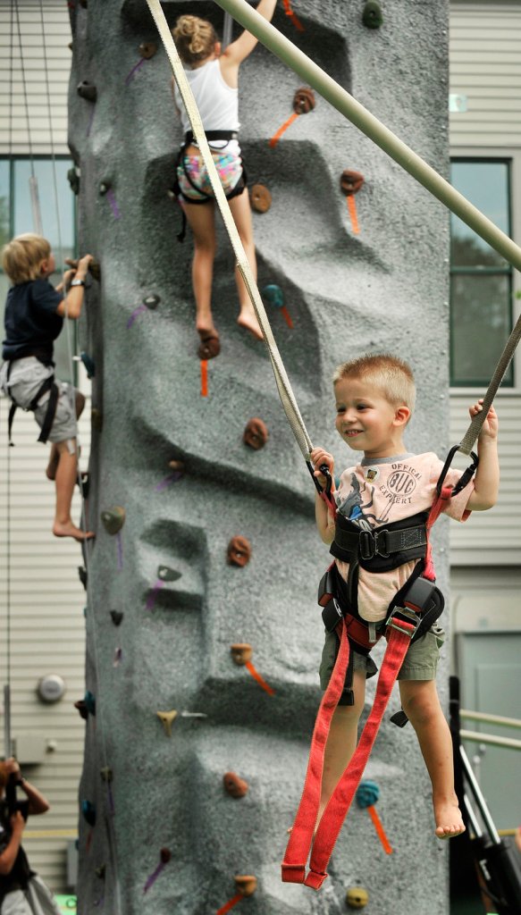 Ryan Phelan, 3, who was visiting with his family from Albany, N.Y., plays on a jumper while other kids climb on a rock wall behind him in Freeport.