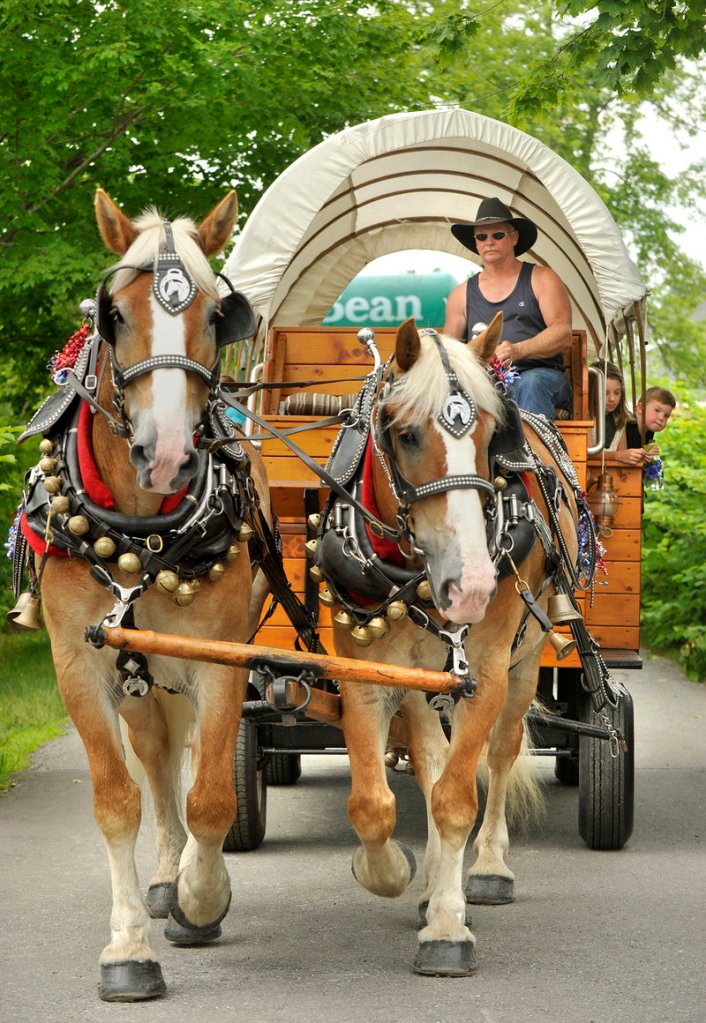 Visitors to L.L. Bean’s celebration of its 100th anniversary in downtown Freeport ride on a horse-drawn wagon from Meadow Creek Farm on Saturday.
