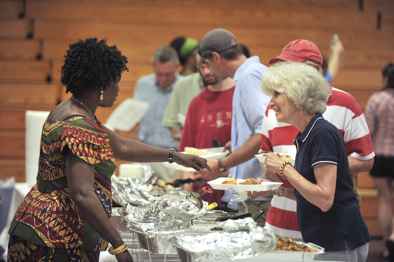 Mary Ben, left, suggests Sudanese food choices to Donna and Brian Gordon of Scarborough, as they make their way down the buffet line at the Southern Maine Community College gymnasium Saturday.