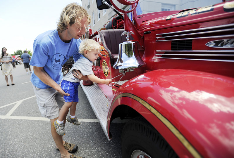Isak Amundsen, 2, of Bath, with the help of his father Scott, rings the bell on a 1941 Bath fire truck on display at the antique car show on Sunday during Bath Heritage Days.