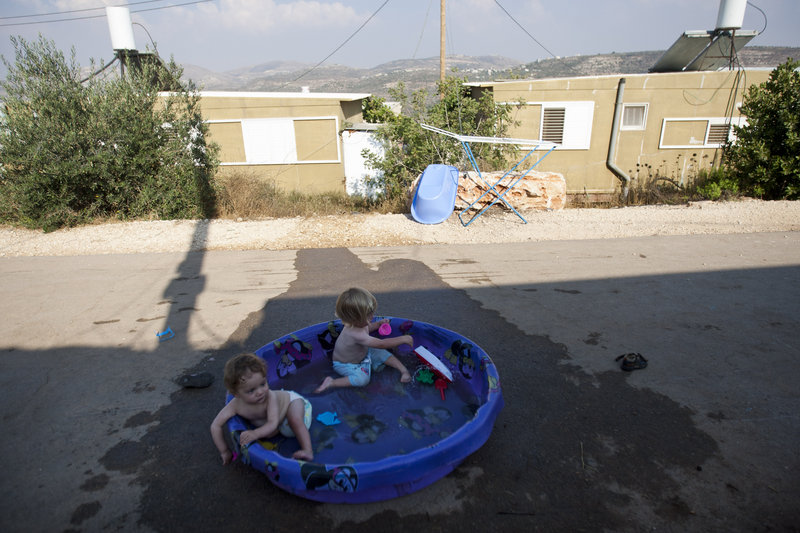 Children of Jewish settlers play in a pool at the unauthorized West Bank outpost of Nofei Nehemya on Monday. A government-appointed committee is recommending that Israel legalize dozens of unauthorized West Bank settlement outposts.