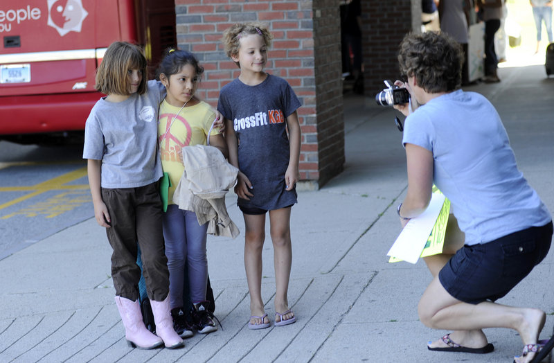 Cheri Poulin of Kennebunk takes a photograph of her daughters Lauren, left, and Katharine, right, both 8, as they pose with their visitor, Maria Castro 7, center, of New York City after Castro arrived in Kennebunk on Tuesday.