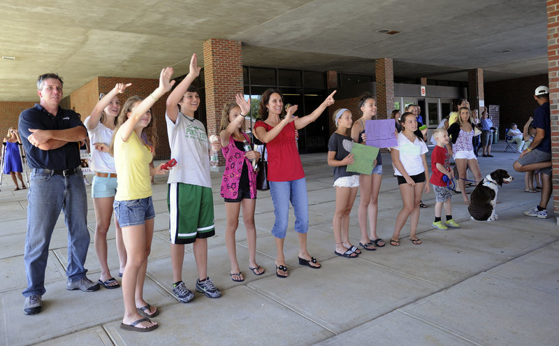 Fresh Air Fund host families wave to their visitors as they arrive on a bus at Kennebunk High School on Tuesday.