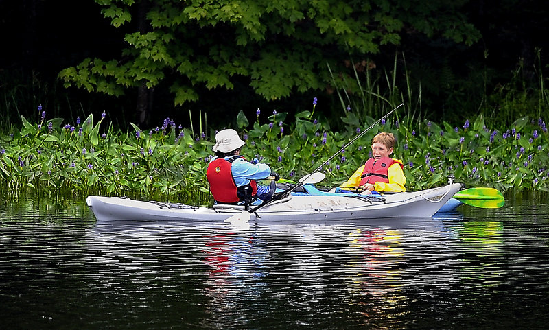 Dana Hinchliffe, right, of Portland watches as his mother, Karen, removes the hook and waits for officials to record his catch of a 4-pound smallmouth bass.