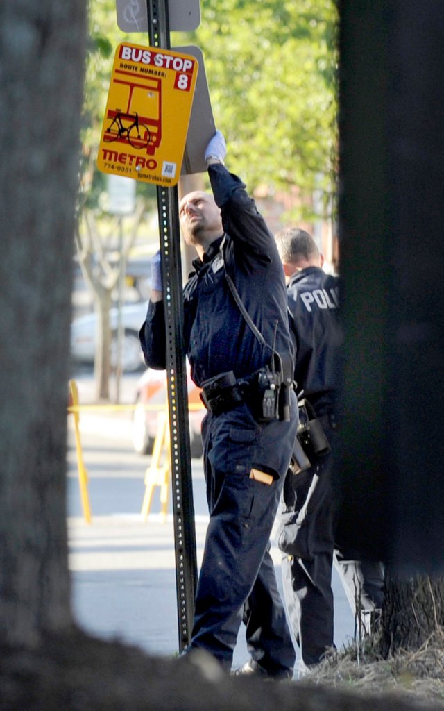 A Portland police officer looks for evidence on a sign post near 105-107 India St. after an early morning shooting Wednesday. Witnesses told police that a loud argument erupted, then several shots were fired.