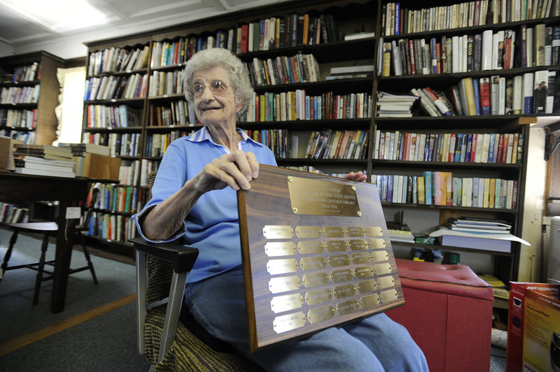 Librarian Lorraine Jonassen, 90, holds a plaque with the names of librarians who have served since 1934 at the South Windham Public Library on the Gorham/Windham line. The library is selling its remaining books and furnishings on Friday and Saturday.