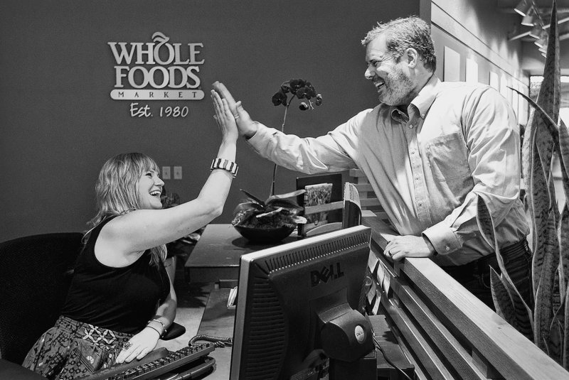 Whole Foods employees Mark Ehrnstein, global vice president for team member services, and Nikki Newman, a receptionist at the corporate headquarters, high-five one another in their Austin, Texas, office.