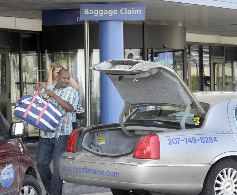 Taxi driver Rashid Olhaye handles the bag of a passenger at the Portland International Jetport.