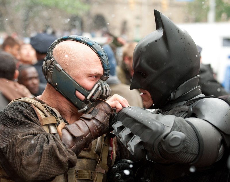 Tom Hardy plays Bane, left, a terrorist who attacks Gotham City and faces off with Batman.