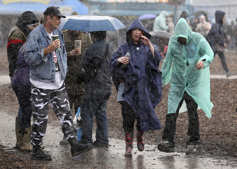 Festival-goers brave the falling rain at the Hard Rock Calling music festival in London on Friday. The weekend music event was planned to be held on the grass of Hyde Park, but the land turned into a muddy quagmire and had to be covered with wood chips to enable the festival to go ahead, as part of the build-up to the Olympic Games.
