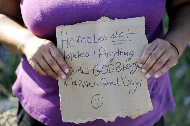 Kelly Noble holds a sign that says: “Homeless, not hopeless!! Anything works. God bless you and have a great day!” while panhandling in Portland.