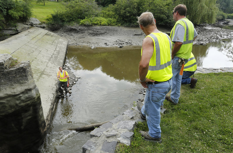 William Peterlein of Summit Geoengineering Services talks to city workers along the Stroudwater River after the water was lowered so the dam could be inspected. The upstream water level has been dropping, leading officials to suspect there is a leaky sluice gate.