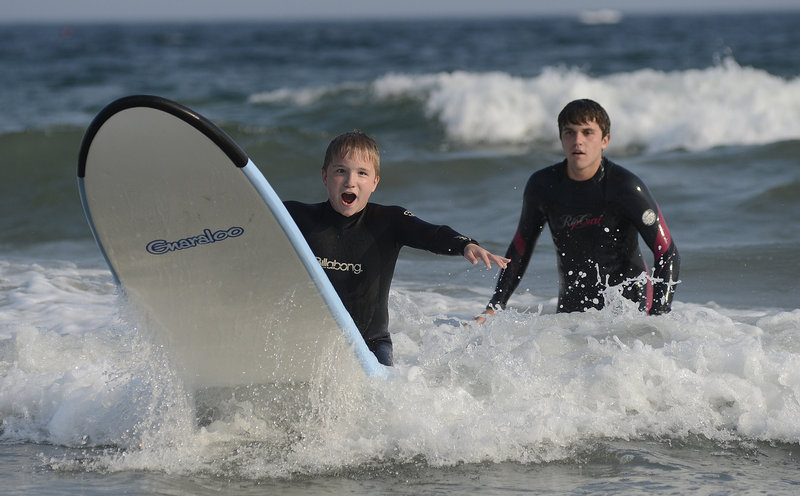 Noah Rassier, 12, of Milford, N.H., rides a wave with guidance from volunteer Daniel Gross of New York City.