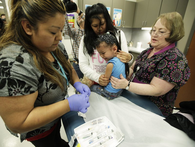 Nurses Fatima Guillen, left, and Fran Wendt give Kimberly Magdeleno, 4, a whooping cough shot as she is held by her mother, Claudia Solorio, at a health clinic in Tacoma, Wash.