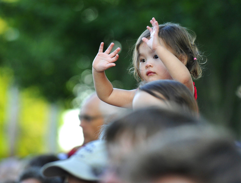 Two-year-old Grace Christensen cheers the Yarmouth Clam Festival parade Friday while she’s seated atop the shoulders of her grandfather Dick Danosky of Yarmouth. More than 100,000 people are expected to attend the three-day event.