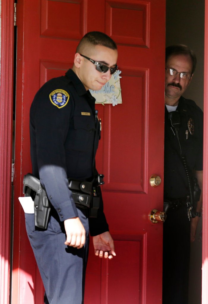 San Diego police officers stand in the doorway of the home of the mother of Colorado shooting suspect James Holmes on Friday in San Diego. “Our hearts go out to those who were involved in this tragedy,” the family said in a statement.