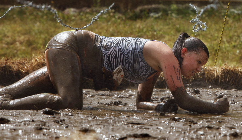 Jaclyn Martin crawls through mud under barbed wire. Competitors ran, walked, hopped, slid, swam and climbed across 3.1 miles that included two mountains during the mud-and-obstacle course.