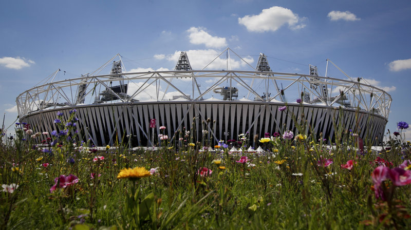 The Olympic Stadium rises beyond an installation of artificial wildflowers in the Olympic Park at the 2012 London Summer Olympics. The opening ceremony is Friday.