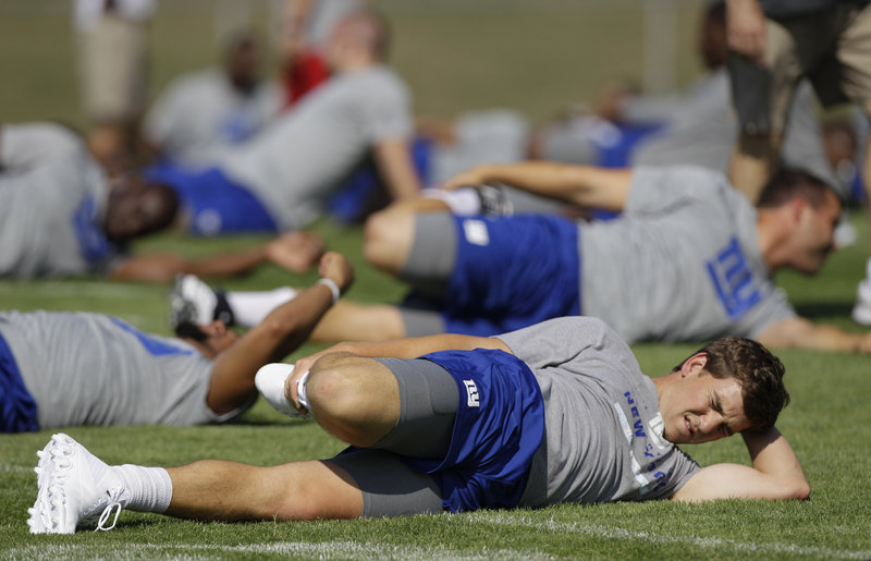 New York Giants quarterback Eli Manning stretches on the field on the opening day of training camp in Albany, N.Y. Manning and the Giants are not the preseason Super Bowl favorites despite winning their second title in five years in February.