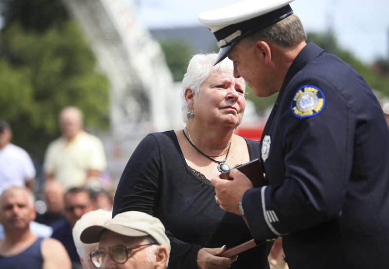 Sandra Jackson of Yarmouth receives a medallion in memory of her former husband, firefighter Frank E. Cowan, who died in 1993, from Lt. Aaron Osgood during the Portland Fire Department’s Fallen Firefighter Memorial dedication at Central Fire Station in Portland on Saturday.