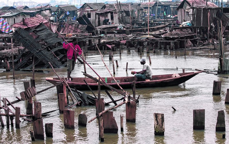 A man paddles a canoe past demolished stilt houses at Makoko in Lagos, Nigeria. The government recently forced thousands of evictions, and may have many more planned.