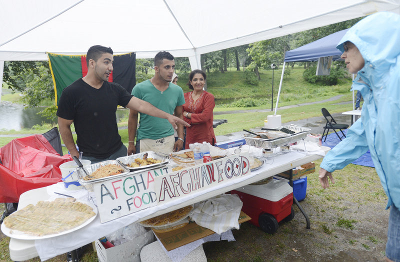 Sadiq Majeed, left, his brother Sameer Majeed and their mother, Hooria Majeed, talk with Susan Adler of Portland about the Afghan food the family is serving at the Festival of Nations in Deering Oaks park on Sunday. The Majeeds moved to Portland from Afghanistan in 2002.