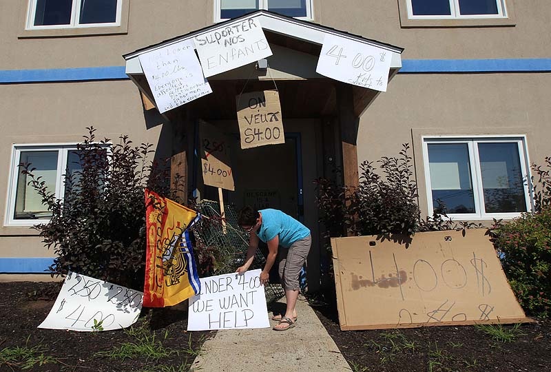Protesters put signs up around the entrance to Ashfield's office. One says, "Under $4.00 – We Want Help."
