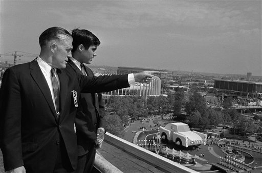 FILE - In this May 18, 1964, file photo Gov. George Romney and his son, Mitt, look out over the New York World's Fair grounds from the heliport after attending a Michigan breakfast at the Top of the Fair Restaurant. The governor and a large delegation from Michigan are here for Michigan Day at the fair. At right is part of the Chrysler exhibit and behind them is the Ford exhibit. Long before Mitt Romney became the millionaire candidate from Massachusetts, he was his father' son, who idolized the outspoken, no-nonsense, auto executive turned politician. (AP Photo, File) politician;visit;world's;fair;view;pointing;father;son