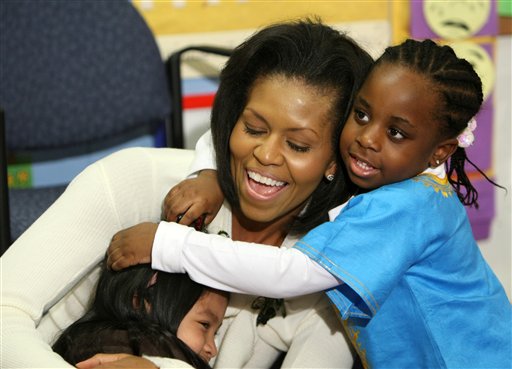 ADVANCE FOR SUNDAY, AUG. 19 AND THEREAFTER - FILE - In this Feb. 10, 2009, file photo, first lady Michelle Obama hugs children after reading a book at Mary's Center in Washington. She is 5-foot-11, and she is world-famous. Sometimes she inspires awe in her admirers. She has been accused of being the angry type. So when Michelle Obama meets people, she likes to bring things down to earth with a hug. (AP Photo/Gerald Herbert, File)