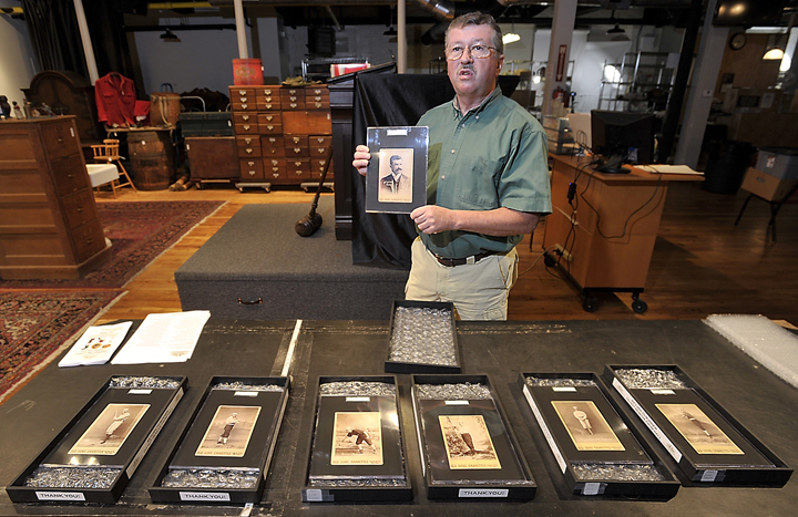Auctioneer Floyd Hartford discusses the value of antique 1888-89 Old Judge Cigarette cabinet cards as he holds a rare Michael "King" Kelly card at the Saco River Auction in Biddeford on Friday.