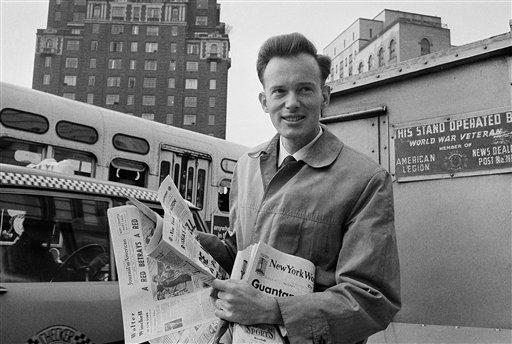 In this May 4, 1964 file photo, Malcolm Browne, then Associated Press correspondent in Vietnam, home on leave, reads New York newspapers at a newsstand near his parents' residence in New York following his Pulitzer Prize award. Browne, acclaimed for his trenchant reporting of the Vietnam War and a photo of a Buddhist monk's suicide by fire that shocked the Kennedy White House into a critical policy re-evaluation, died Monday night, Aug. 27, 2012 at a hospital in New Hampshire, not far from his home in Thetford, Vt. He was 81. (AP Photo)