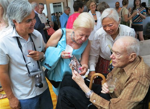 In this Aug. 11, 2012 photo, former Associated Press Saigon bureau chief Malcolm Browne, right, and his wife Lelieu, second from right, look at a photo shown to him by Edith M. Lederer showing her in Vietnam where she too served as an AP correspondent along with with AP photographer Nick Ut, left, at a memorial tribute in New York to former AP Vietnam staffers Horst Faas and George Esper. Browne died Monday, Aug 27, 2012, in a New Hampshire hospital at age 81. He was acclaimed for his trenchant reporting of the Vietnam War and a photo of a Buddhist monk's suicide by fire that shocked the Kennedy White House into a critical policy re-evaluation. (AP Photo/Valerie Komor)