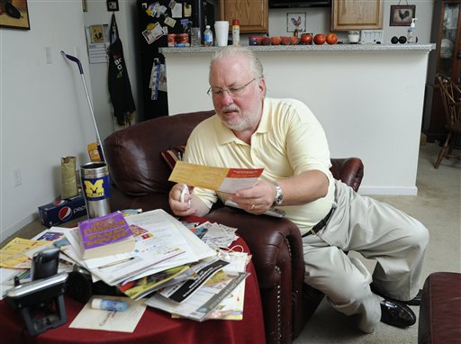 Greg Mann, an unemployed research analyst and real estate appraiser, sorts and cuts coupons at his home on Tuesday in Braselton, Ga.