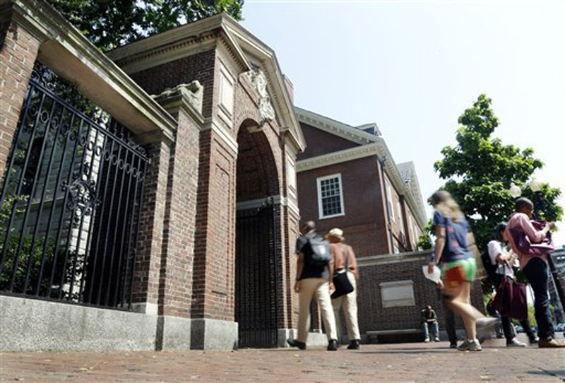 Pedestrians walk through a gate on the campus of Harvard University in Cambridge, Mass., on Thursday.